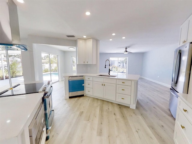 kitchen with stainless steel appliances, a sink, white cabinetry, light wood-type flooring, and range hood