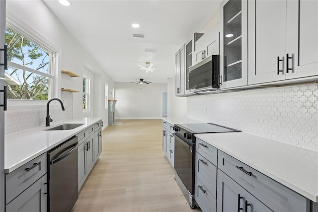 kitchen featuring visible vents, light wood-style flooring, gray cabinetry, appliances with stainless steel finishes, and a sink