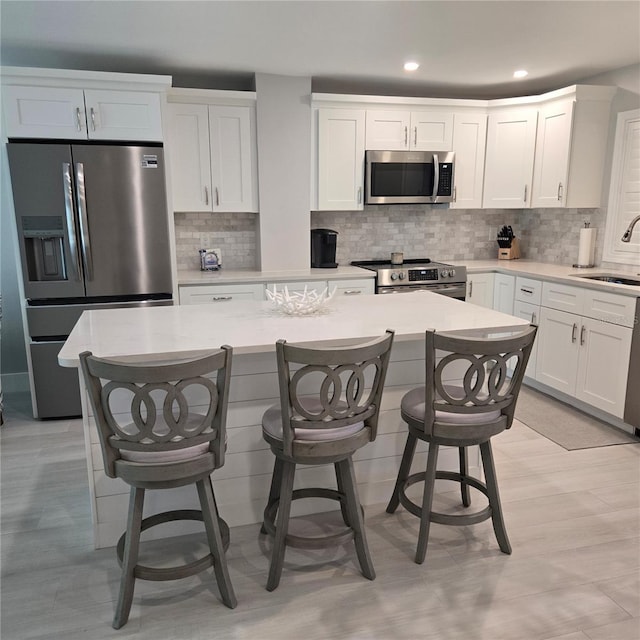 kitchen featuring appliances with stainless steel finishes, white cabinets, a sink, and light countertops