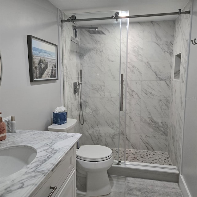 full bathroom featuring toilet, a marble finish shower, and vanity