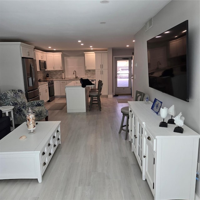 living area with light wood-style flooring, recessed lighting, and visible vents
