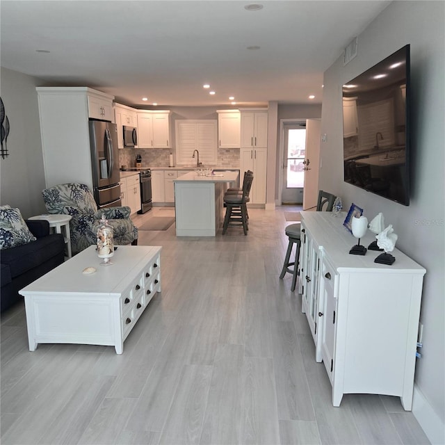 living room with recessed lighting, visible vents, and light wood finished floors