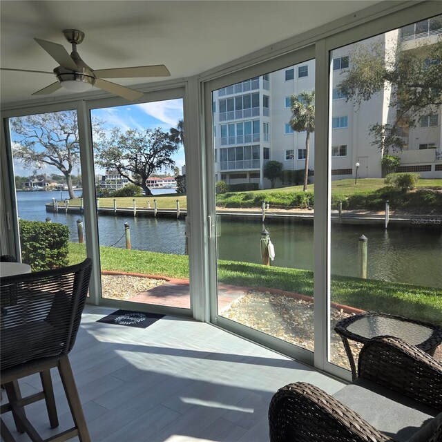 sunroom featuring a water view and ceiling fan