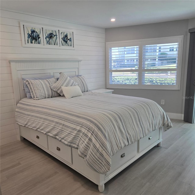 bedroom with wooden walls, wood finished floors, and baseboards