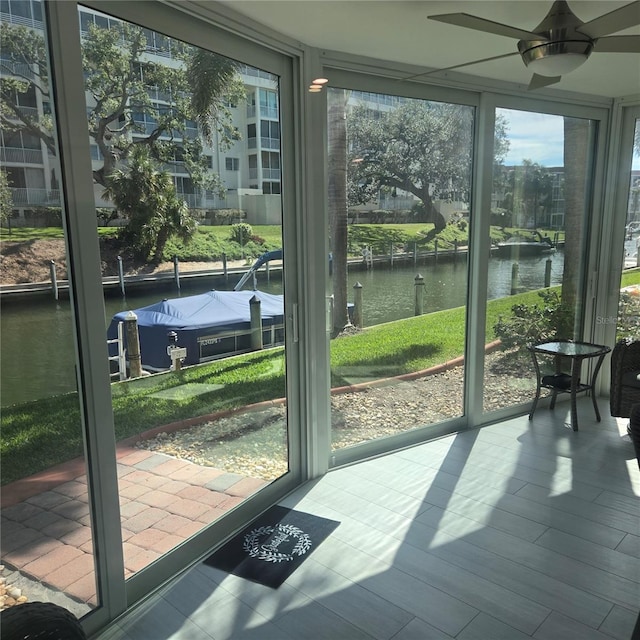 sunroom / solarium featuring a water view and a ceiling fan