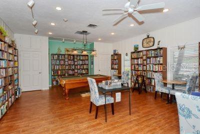 living area featuring visible vents, wood finished floors, and wall of books