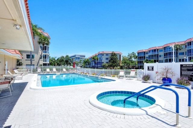 community pool featuring a patio area, fence, and a hot tub