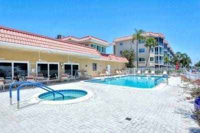 pool with a patio, fence, and a hot tub