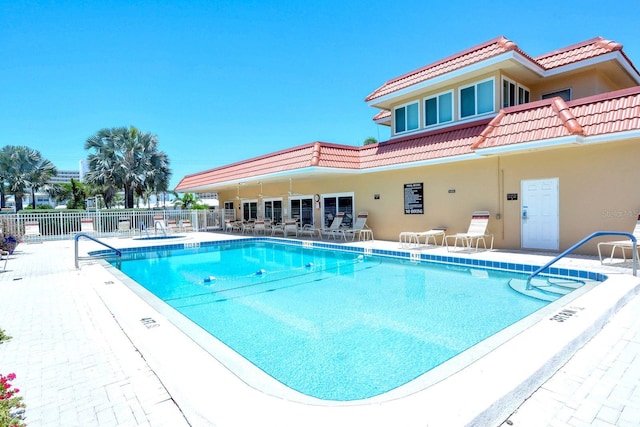 community pool with a patio area and fence
