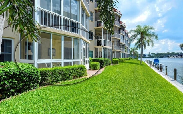 view of community featuring a lawn, a boat dock, and a water view