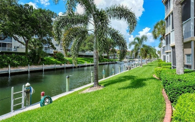 surrounding community featuring a lawn, a boat dock, and a water view