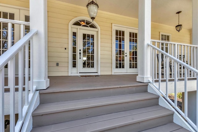 property entrance with covered porch and french doors