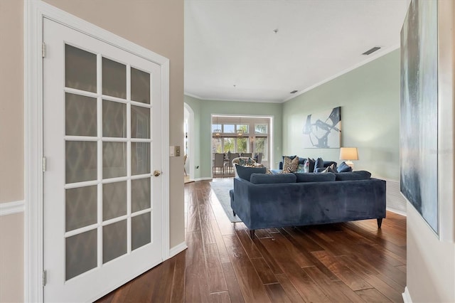 living area with arched walkways, dark wood-style flooring, crown molding, visible vents, and baseboards