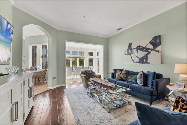 living area featuring arched walkways, crown molding, dark wood finished floors, visible vents, and baseboards