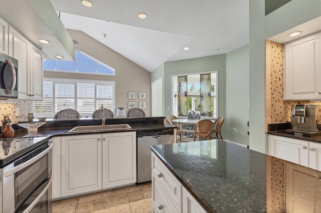 kitchen with stone tile flooring, white cabinetry, stainless steel appliances, and a wealth of natural light