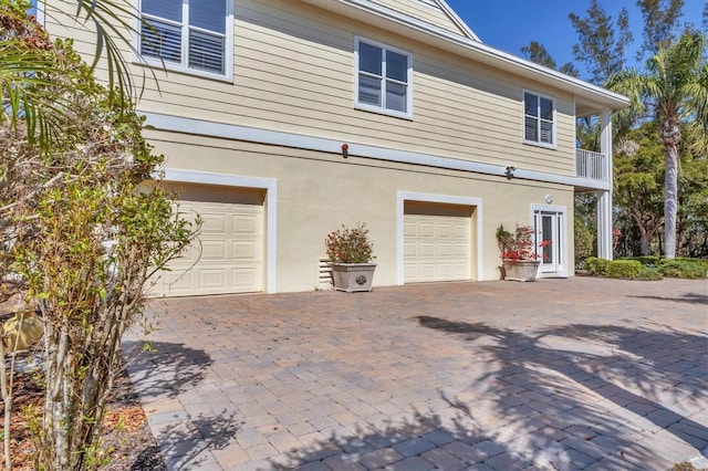 exterior space featuring decorative driveway, an attached garage, and stucco siding