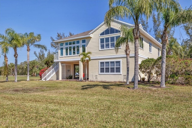 view of front of home featuring stairs, a front lawn, and stucco siding