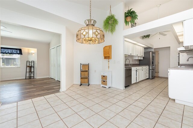 1730 Hudson St, Englewood, FL 34223 - kitchen with stainless steel appliances, a sink, white cabinetry, a ceiling fan, and high vaulted ceiling
