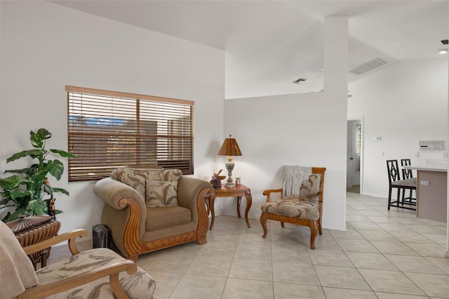 sitting room with light tile patterned floors, visible vents, and high vaulted ceiling