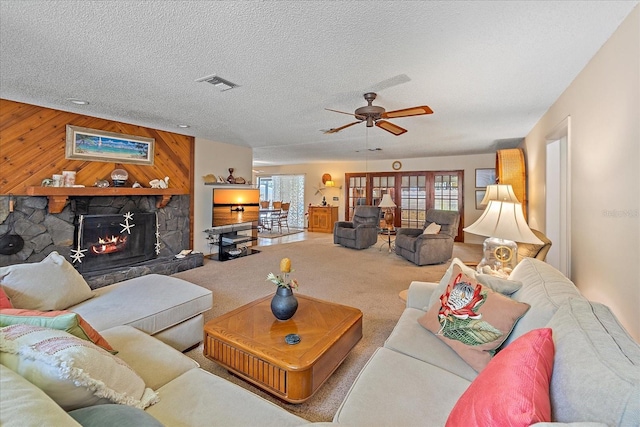 living area with carpet floors, a fireplace, visible vents, wood walls, and a textured ceiling