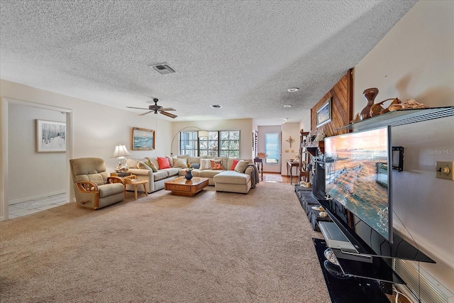 living area featuring a textured ceiling, carpet floors, visible vents, and a ceiling fan