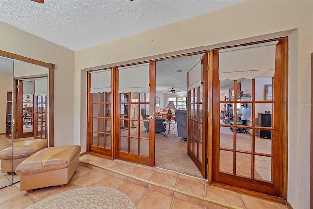 doorway featuring tile patterned flooring, french doors, ceiling fan, and a textured ceiling