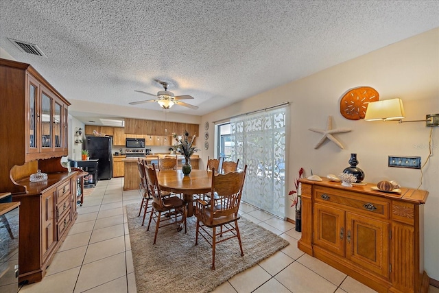 dining room with light tile patterned floors, a textured ceiling, visible vents, and a ceiling fan