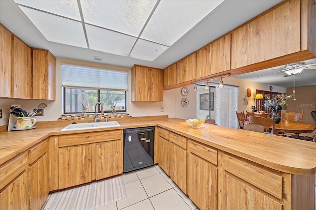 kitchen with butcher block counters, dishwasher, a peninsula, and a sink