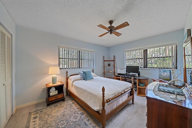 bedroom featuring baseboards, light colored carpet, ceiling fan, a textured ceiling, and a closet