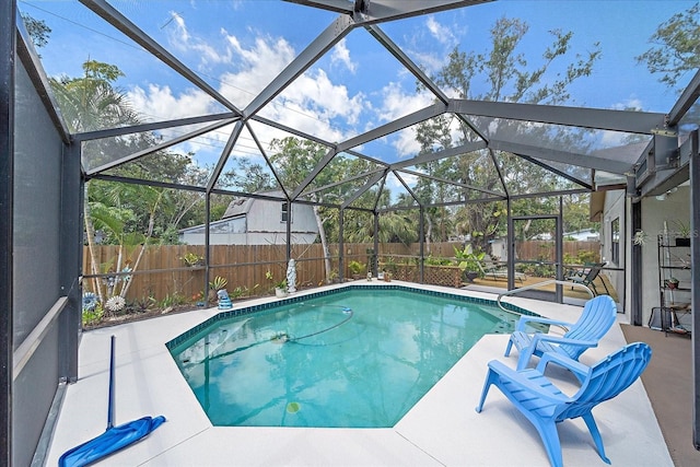 view of pool featuring glass enclosure, a fenced backyard, a fenced in pool, and a patio