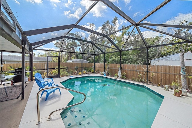 view of swimming pool featuring a patio, glass enclosure, a fenced backyard, and a fenced in pool