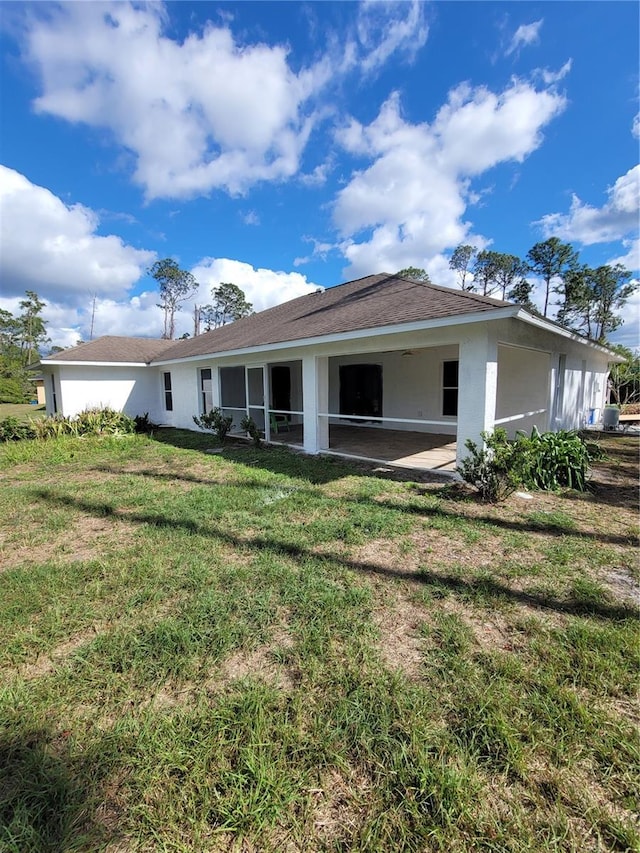 back of house with a sunroom, a yard, and stucco siding