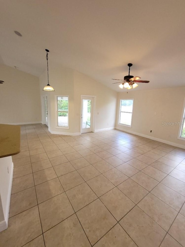 empty room featuring vaulted ceiling, ceiling fan, light tile patterned floors, and baseboards