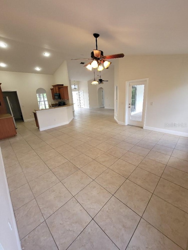 unfurnished living room with plenty of natural light, vaulted ceiling, arched walkways, and ceiling fan