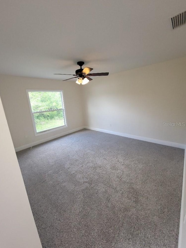 unfurnished room with ceiling fan, carpet floors, visible vents, and baseboards