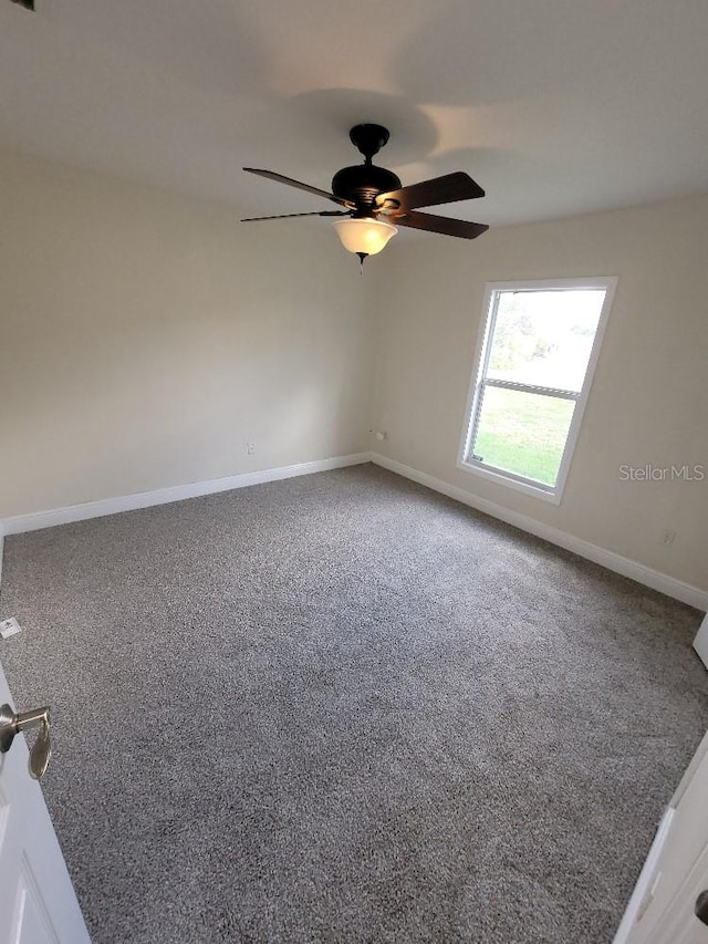 carpeted empty room with ceiling fan and baseboards