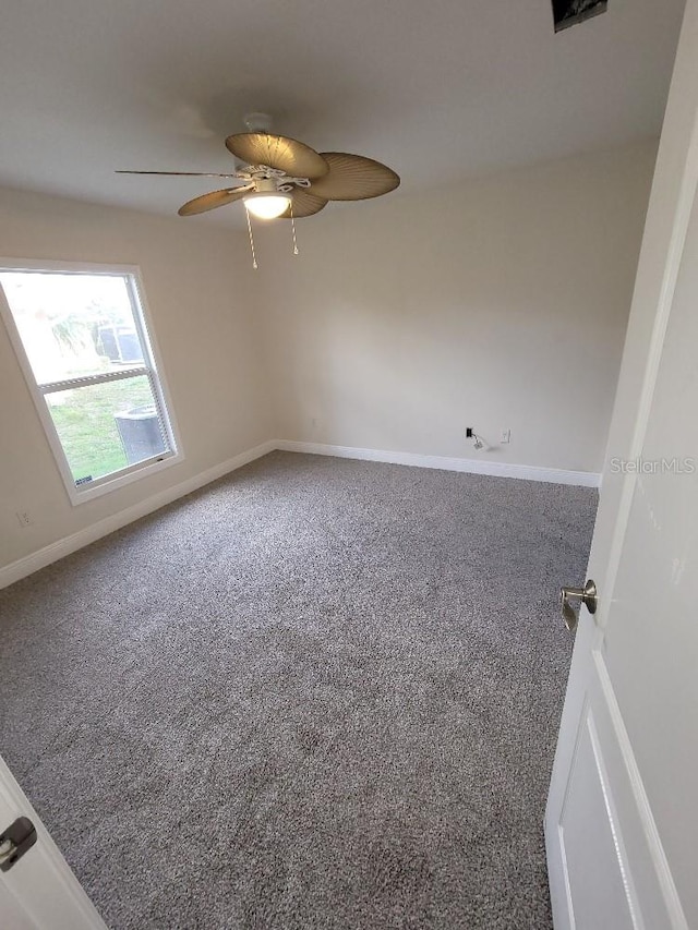 carpeted empty room featuring ceiling fan and baseboards