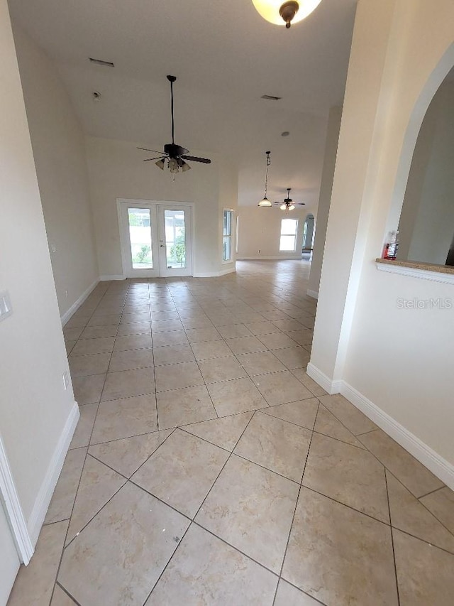 unfurnished room featuring arched walkways, ceiling fan, baseboards, and light tile patterned floors