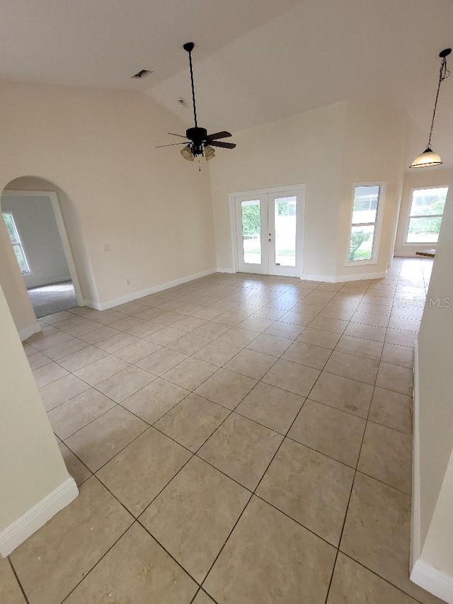 empty room with arched walkways, high vaulted ceiling, and light tile patterned floors