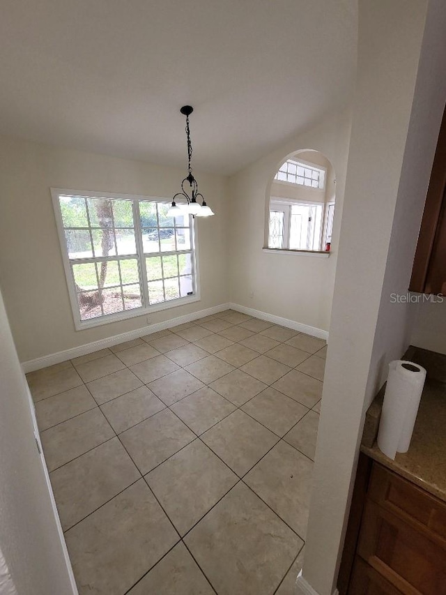 unfurnished dining area with light tile patterned floors, baseboards, and vaulted ceiling