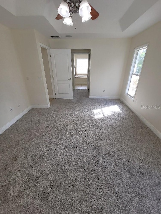 unfurnished bedroom featuring carpet floors, a ceiling fan, visible vents, and baseboards