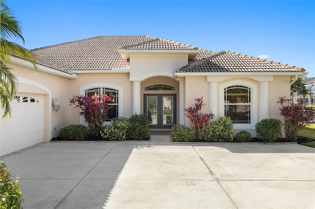 mediterranean / spanish-style house featuring an attached garage, stucco siding, driveway, and french doors