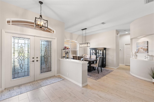 foyer featuring an inviting chandelier, visible vents, wood finished floors, and french doors