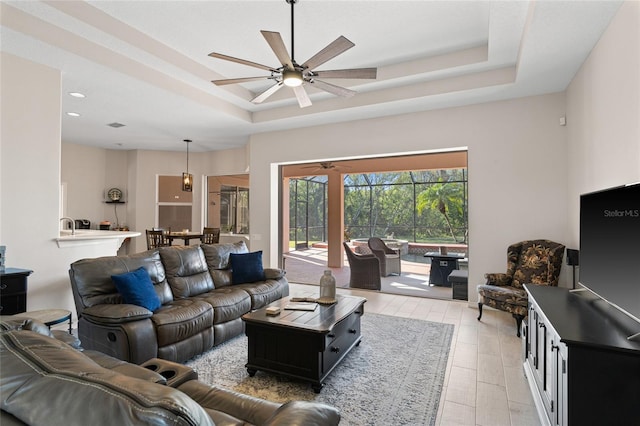 living area with a tray ceiling and a ceiling fan