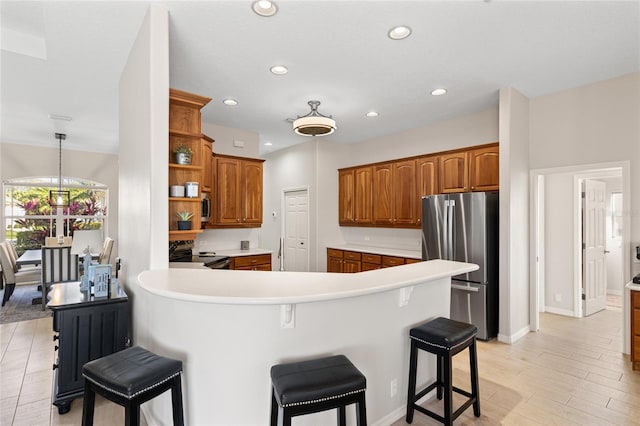 kitchen featuring a peninsula, appliances with stainless steel finishes, brown cabinetry, and open shelves