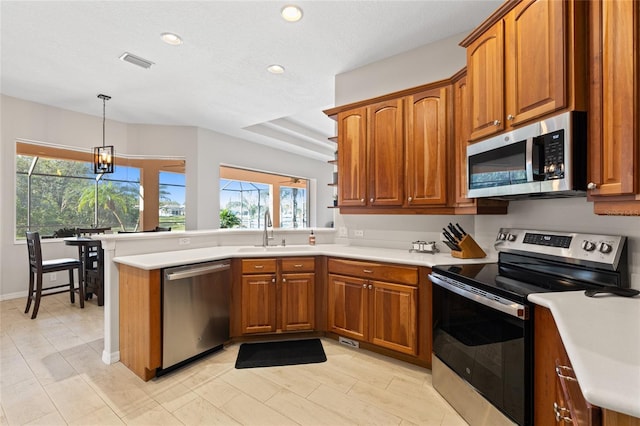 kitchen featuring stainless steel appliances, brown cabinets, visible vents, and a peninsula