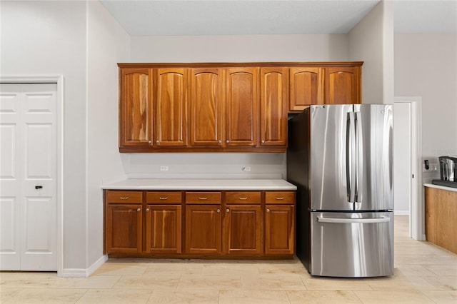 kitchen featuring brown cabinets, light countertops, and freestanding refrigerator