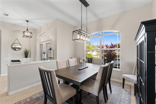 dining space with baseboards, light wood-style flooring, visible vents, and a notable chandelier