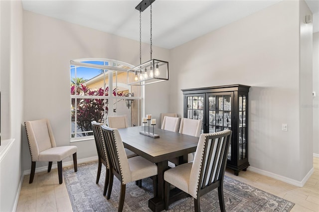 dining room featuring an inviting chandelier, light wood-style flooring, and baseboards