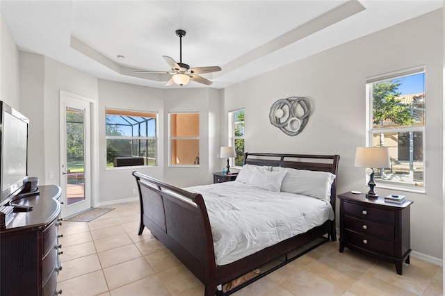 bedroom with light tile patterned floors, ceiling fan, baseboards, access to outside, and a tray ceiling